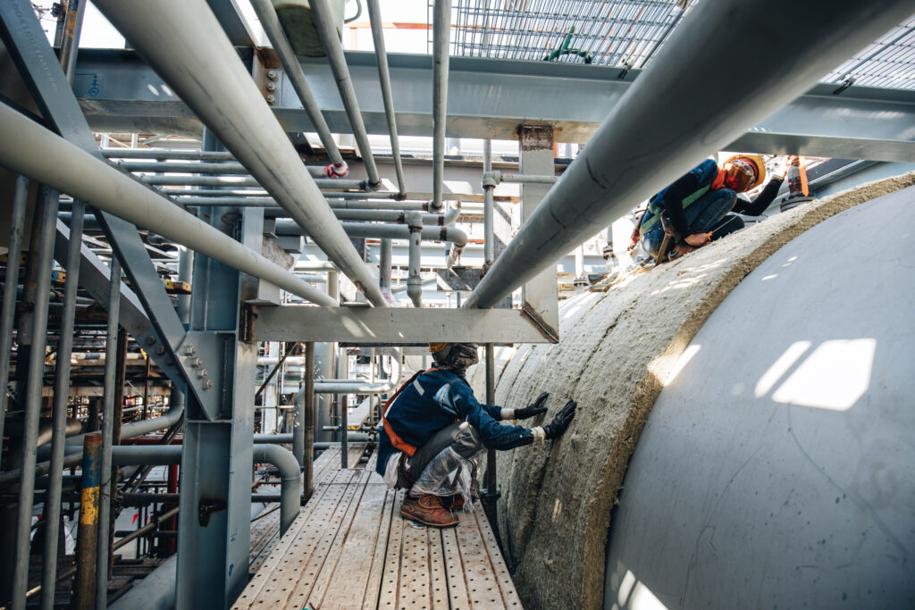 Male workers lay the sheets on the insulation top tank.